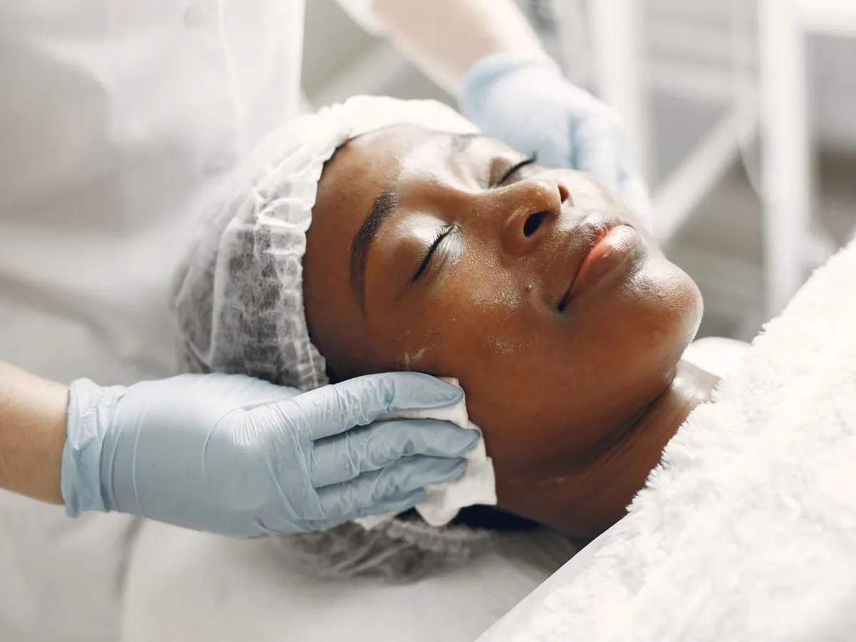 A beautician cleansing a client’s face